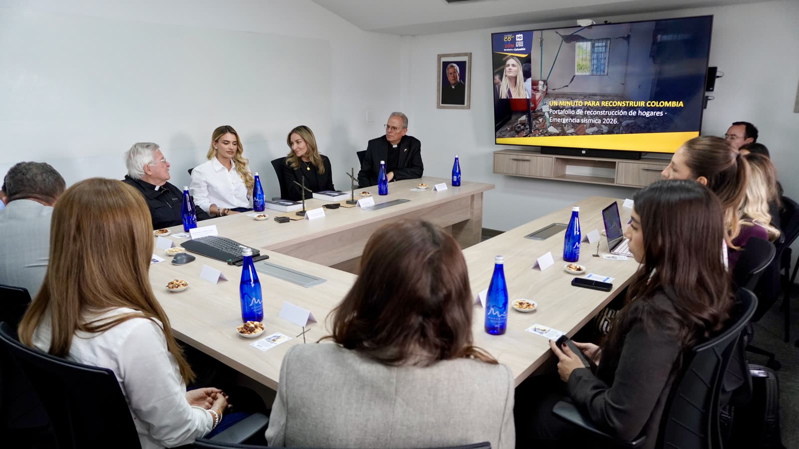 Reunión de trabajo alrededor de la mesa de juntas, con la presentación del portafolio proyectada en pantalla